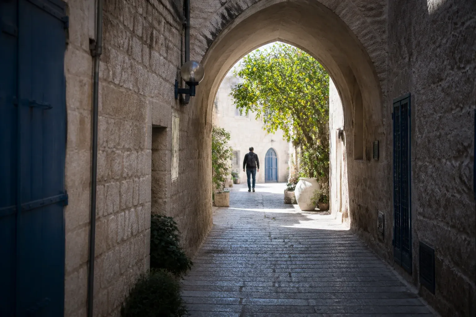מעבר מקושת באבן בסמטה עתיקה המוביל לחצר מוארת